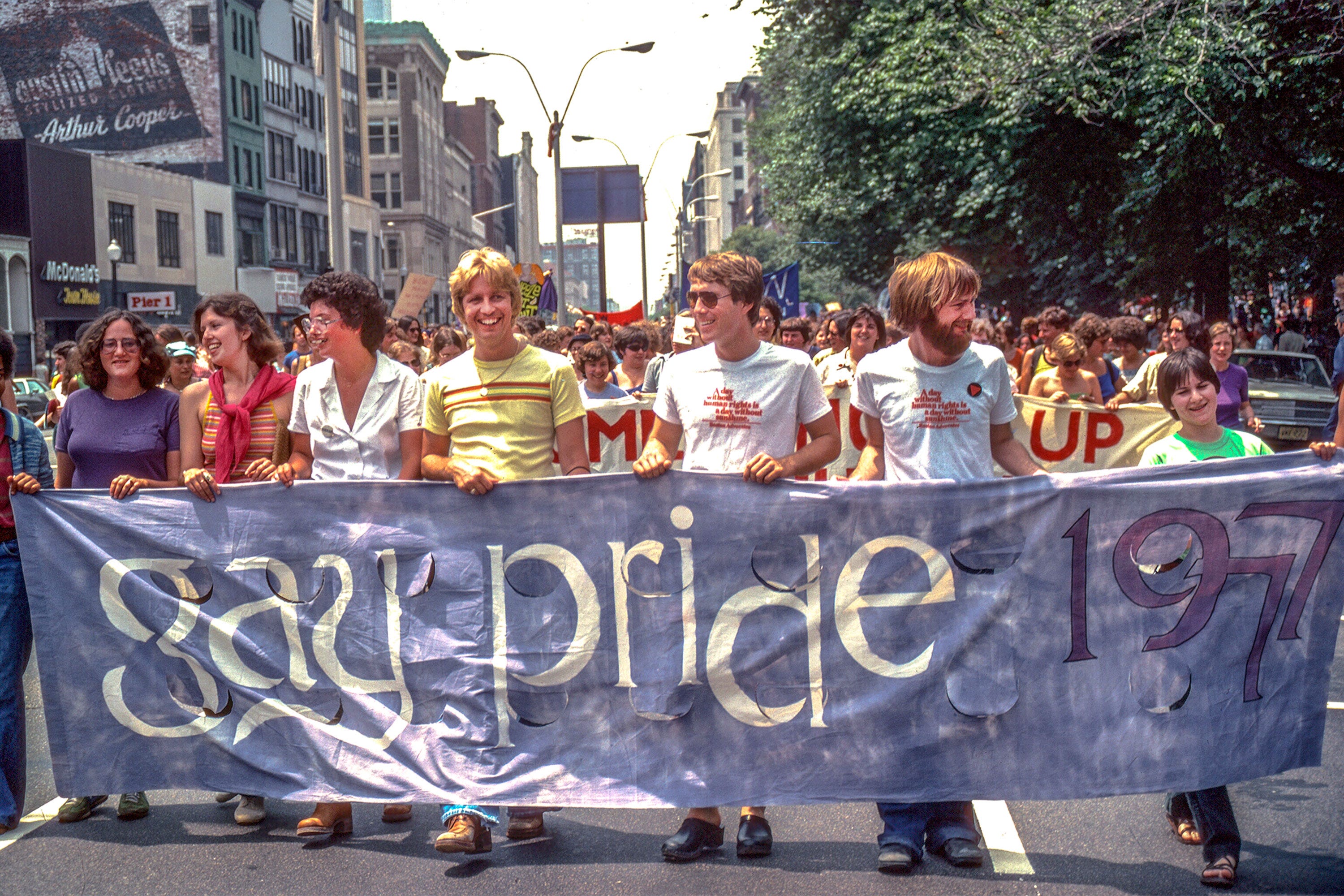 Marchers carry a Gay Pride 1977 banner down the street